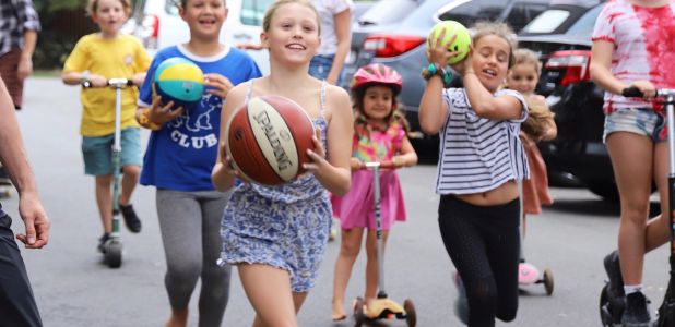 Six children playing in the streets of Waverley with basketballs, footballs and scooters