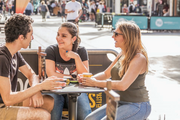 A young man and two young women enjoy coffee together at an outdoor table at a cafe in Bondi Junction Mall