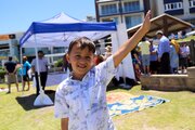 Imagine of young Aghani boy waving to camera while enjoying a picnic at Biddigal Reserve, North Bondi