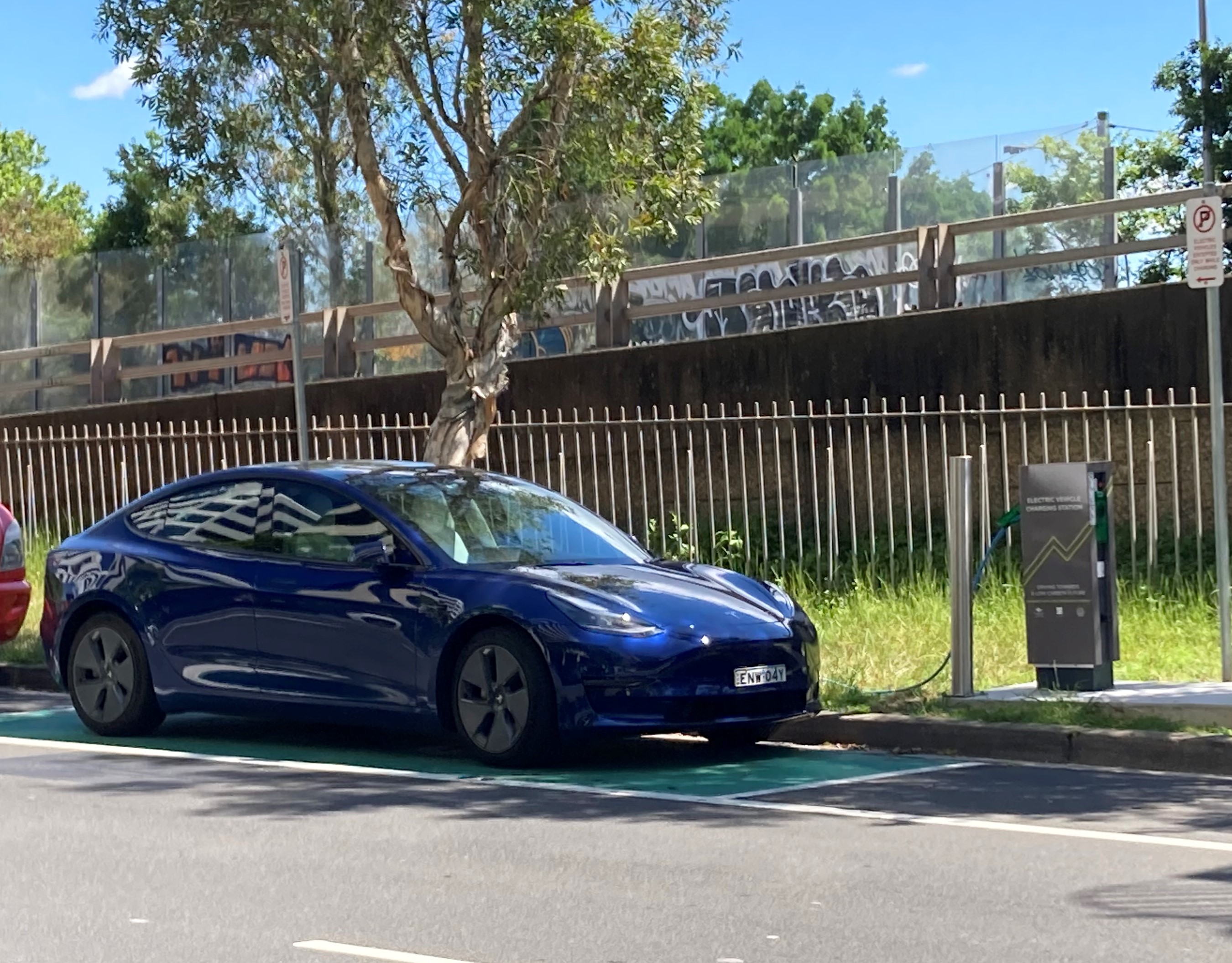 Blue Tesla electric vehicle charging on EV charger on Grafton Street Bondi Junction