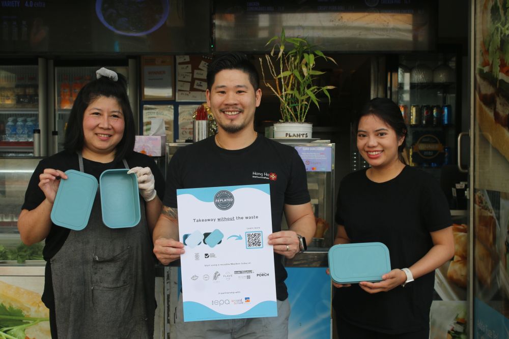 3 cafe staff members with REplated container looking at the camera