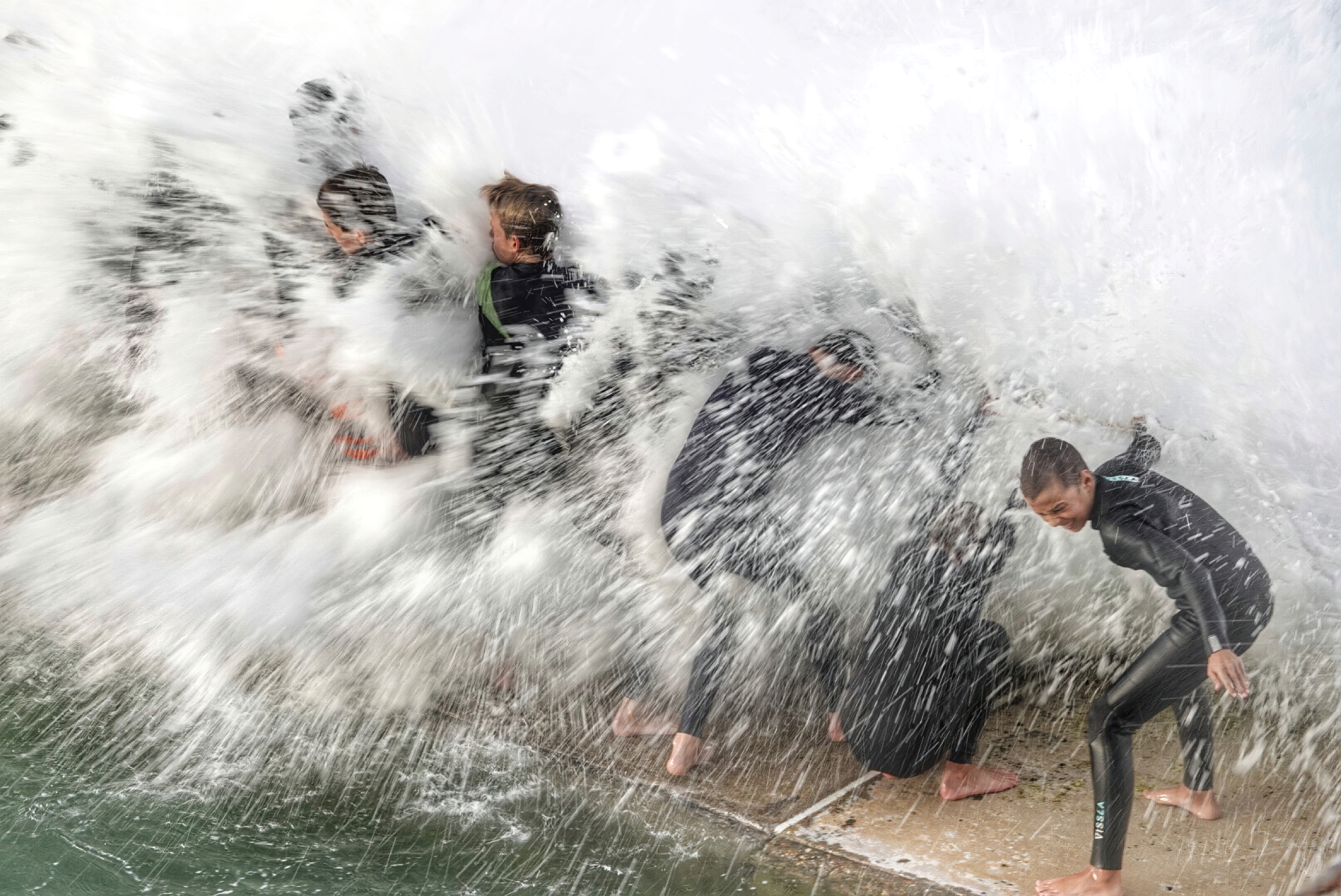 chuildren being hit by a wave playing at a swimming pool 