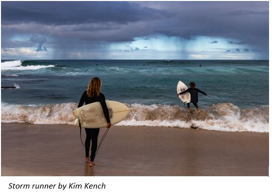 Kids heading into the ocean with storm in the background