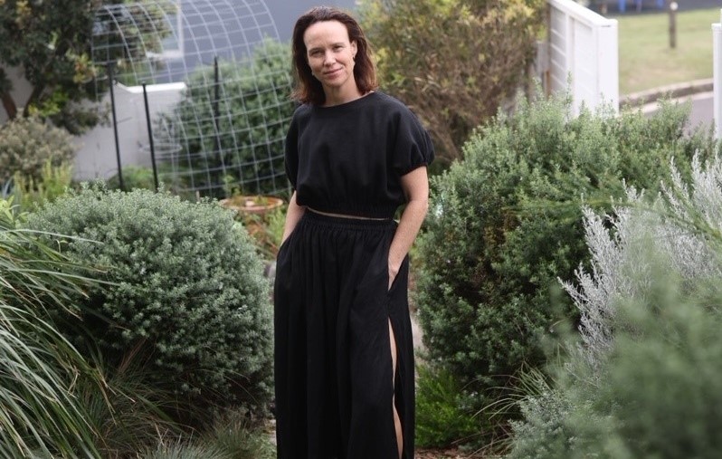 Megan wearing black top and skirt in her front garden surrounded by native shrubs