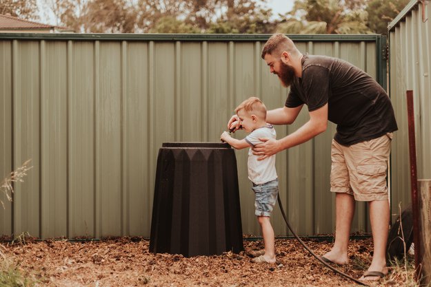 Father and son using a compost bin