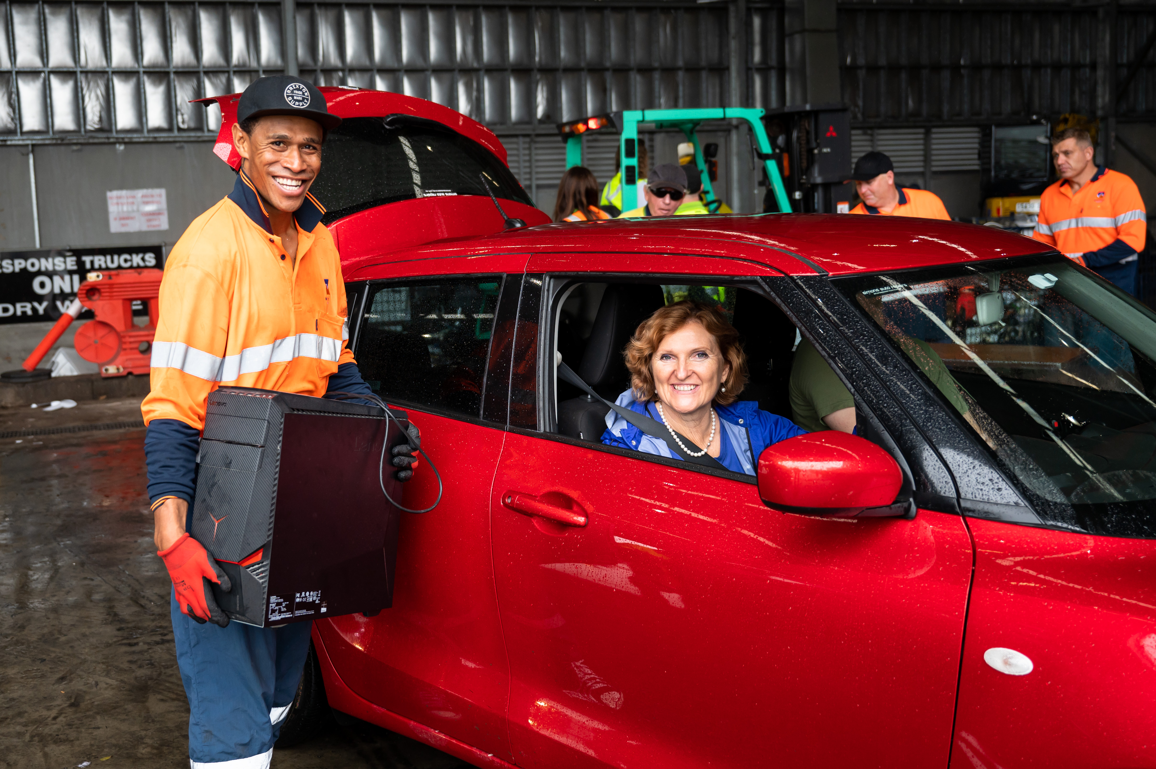 Man holding a computer unit and a woman in a car