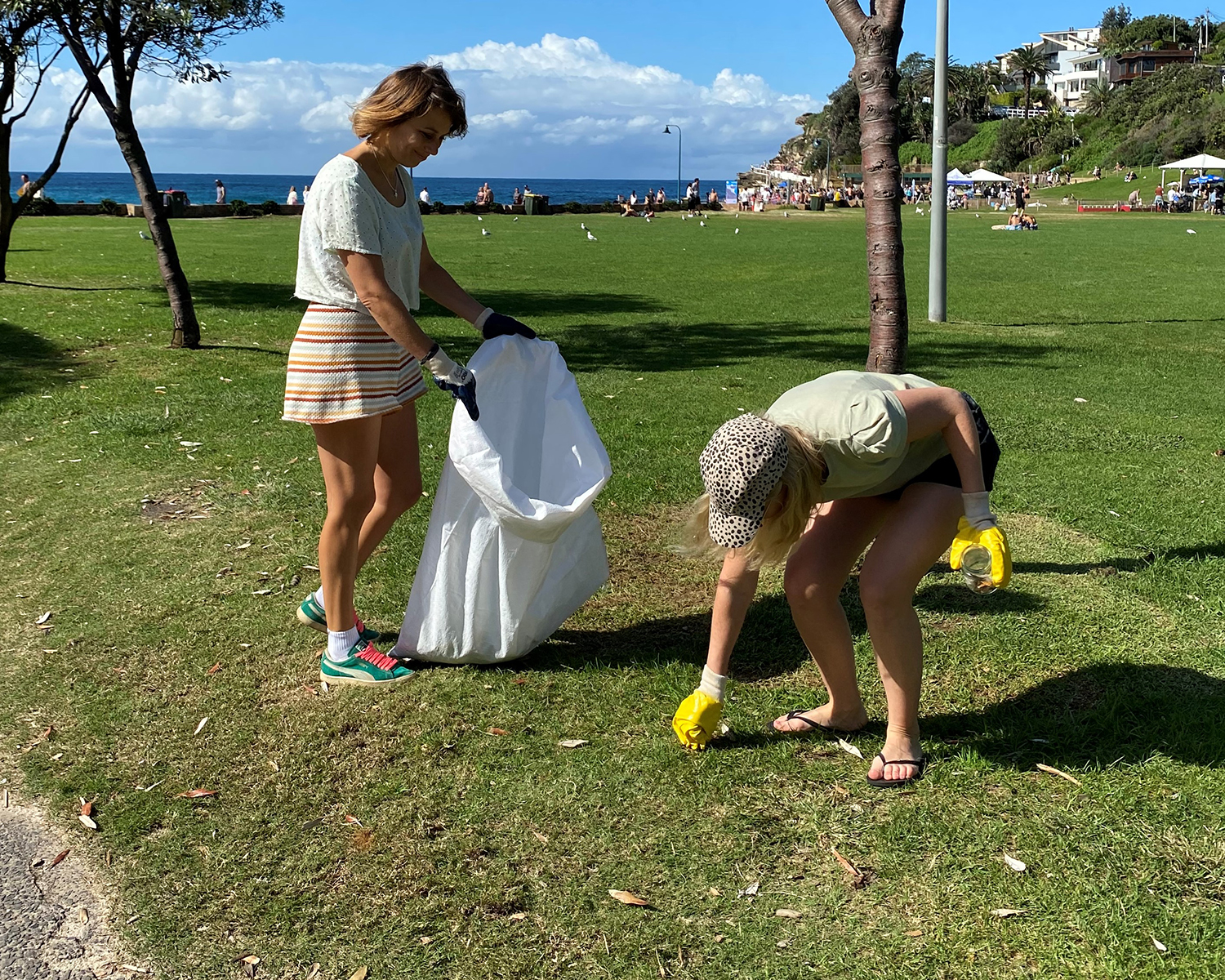 Two young women picking up rubbish at a park near Bronte Beach