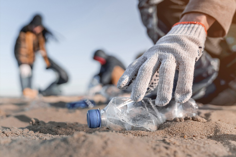 Volunteer man collecting trash on the beach
